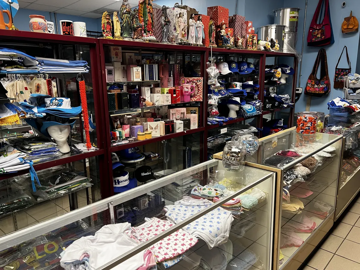 Interior de la tienda con vitrinas de vidrio, gorras y recuerdos de El Salvador