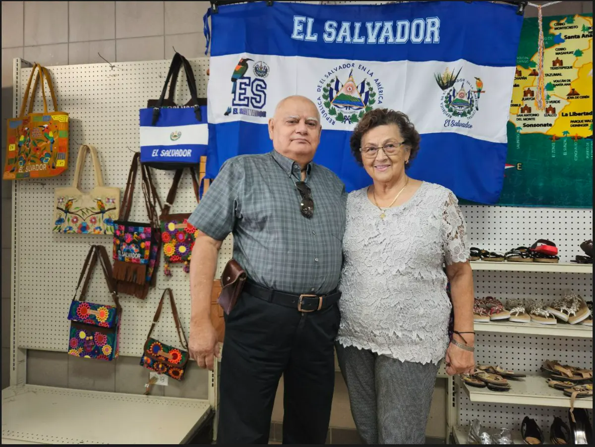 Jorge y Delia Romero, fundadores de Tienda Salvadoreña, de pie frente a una bandera de El Salvador dentro de la tienda