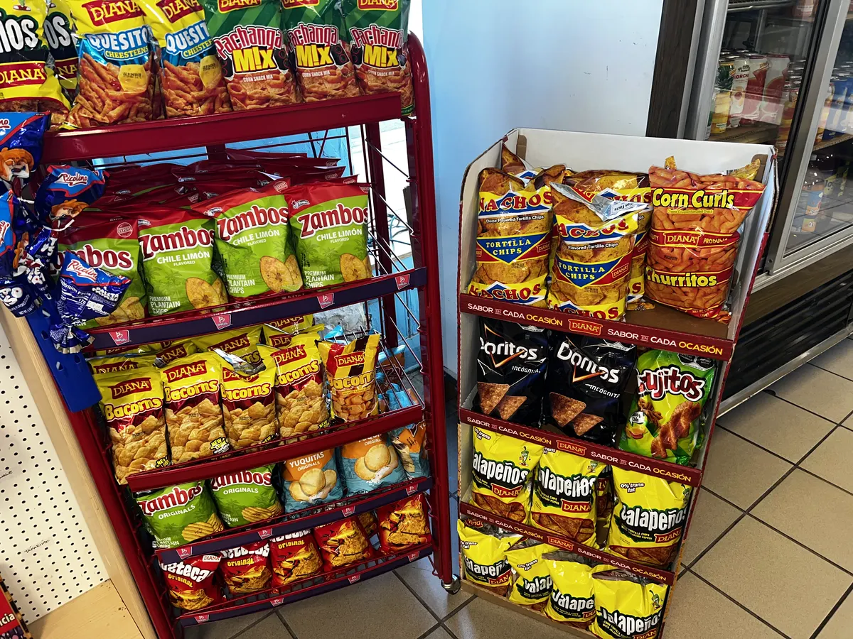 Exhibidores llenos de chips de plátano y bocadillos centroamericanos dentro de la tienda